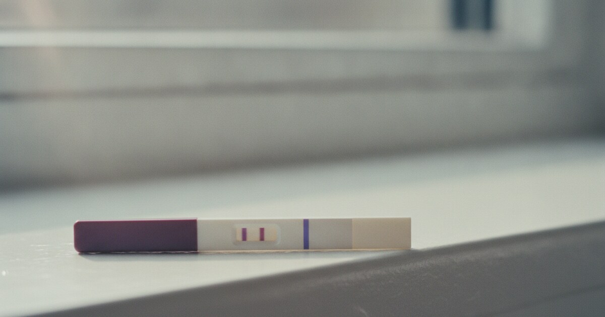A home pregnancy test on a white surface showing the test line darker than the control line