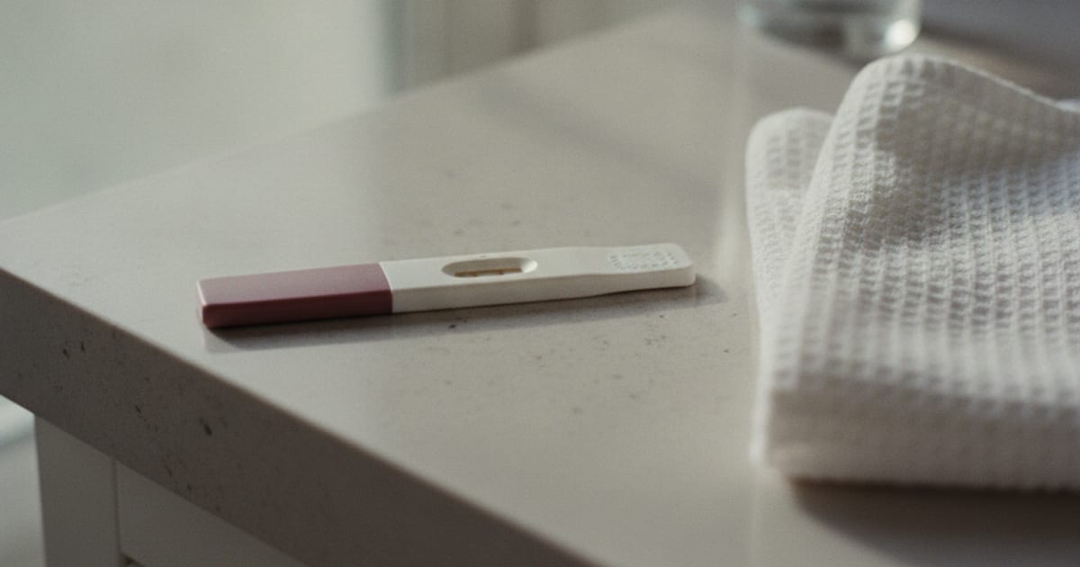 A home pregnancy test resting on a bathroom counter in soft morning window light